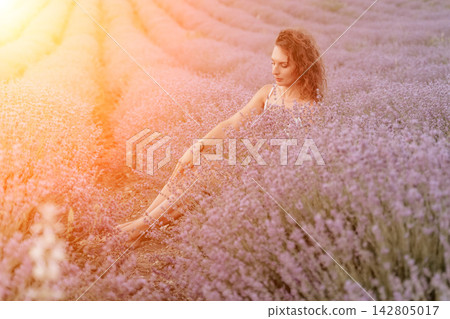 Lavender field woman sitting among purple flowers enjoying peaceful summer sunshine in a vibrant blooming Provencal landscape during golden hour Lavender field woman sitting among purple flowers enjoying peaceful summer sunshine in a vibrant blooming Provencal landscape during golden hour 142805017