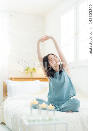 坐在床上的微笑的婦女 坐在床上的微笑的婦女 142805266