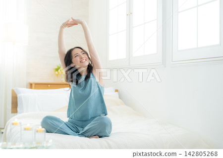 坐在床上的微笑的婦女 142805268