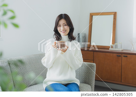 中年婦女在客廳喝咖啡 中年婦女在客廳喝咖啡 142805305