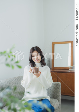 Middle-aged woman drinking coffee in the living room 142805308