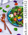 Arugula and Tomato Salad with Edible Flowers on Gray Background 142805452