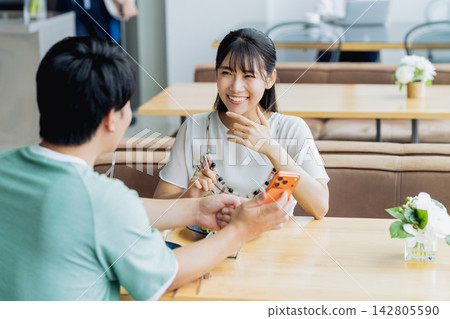 一對年輕夫婦在咖啡館看智能手機 142805590