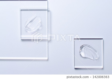A sample of a transparent cosmetic skin care product on glass. Blue background A sample of a transparent cosmetic skin care product on glass. Blue background 142806363