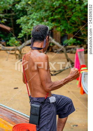 Beach local boatman preparing longtail boat for journey Beach local boatman preparing longtail boat for journey 142806582