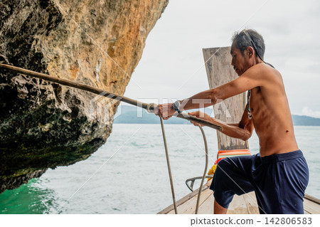 Fisherman pulling rope from longtail boat in thailand Fisherman pulling rope from longtail boat in thailand 142806583