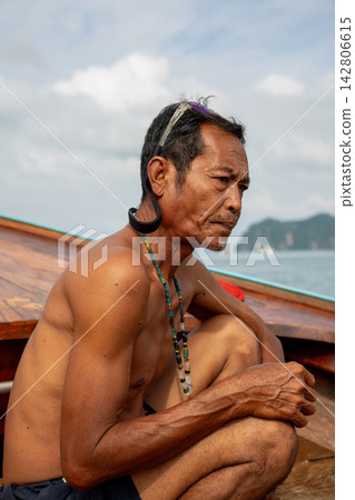 Fisherman sitting on longtail boat in thailand Fisherman sitting on longtail boat in thailand 142806615