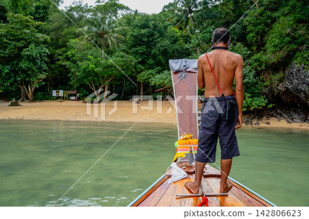 Man navigating longtail boat towards tropical beach in thailand Man navigating longtail boat towards tropical beach in thailand 142806623