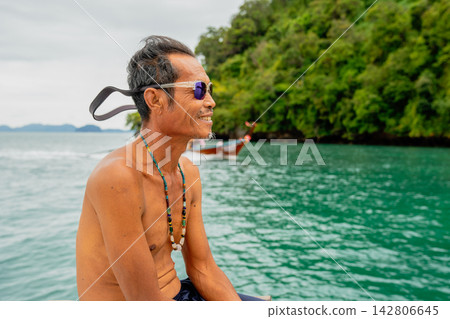 Man smiling enjoying a tropical boat ride near an island Man smiling enjoying a tropical boat ride near an island 142806645