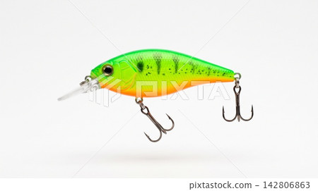 Studio shot of a bright neon green and orange artificial fishing lure suspended over a pure white background. Studio shot of a bright neon green and orange artificial fishing lure suspended over a pure white background. 142806863