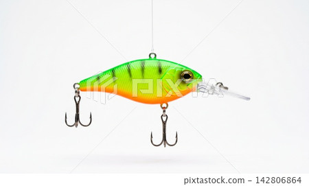 Studio shot of a bright neon green and orange artificial fishing lure suspended over a pure white background. Studio shot of a bright neon green and orange artificial fishing lure suspended over a pure white background. 142806864