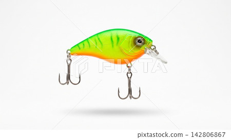 Studio shot of a bright neon green and orange artificial fishing lure suspended over a pure white background. Studio shot of a bright neon green and orange artificial fishing lure suspended over a pure white background. 142806867
