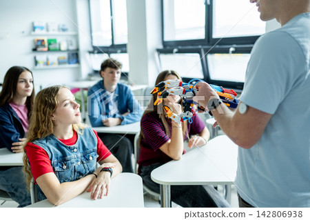 Teen boy presenting robotic project in front of classroom. 142806938