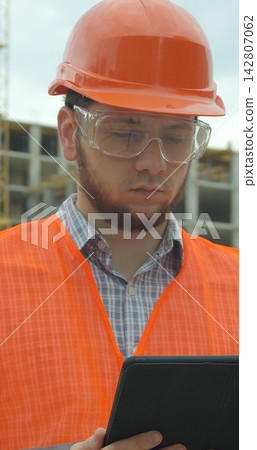 Vertical video. Architect analyzing project plan on construction site with touchpad. Vertical video. Architect analyzing project plan on construction site with touchpad. 142807062