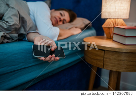 Tired middle aged woman sleeping in bed after using smartphone. Tired middle aged woman sleeping in bed after using smartphone. 142807093