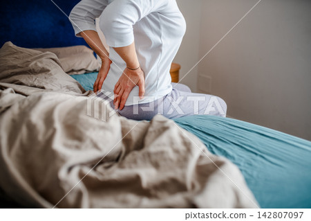 Woman waking up with backpain in the morning. Woman waking up with backpain in the morning. 142807097