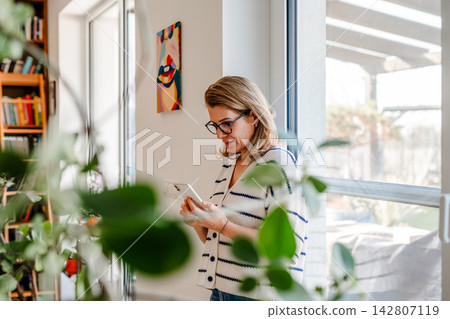 Woman using smartphone while taking a break and checking messages. Woman using smartphone while taking a break and checking messages. 142807119