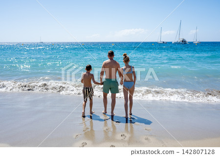Family walking into sea together on sunny beach vacation. Family walking into sea together on sunny beach vacation. 142807128