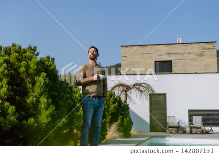 Relaxed man drinking coffee on terrace at home on sunny day. Relaxed man drinking coffee on terrace at home on sunny day. 142807131