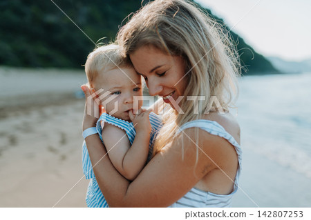 Tender moment between young mom and daughter on sunny beach vacation Tender moment between young mom and daughter on sunny beach vacation 142807253