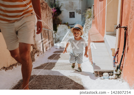 Close up on legs of father and toddler walking in town on summer holiday. 142807254