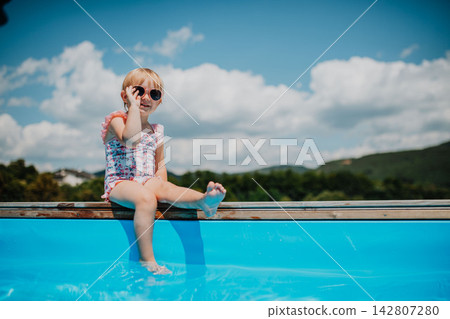 Little girl enjoying summer by the pool Little girl enjoying summer by the pool 142807280