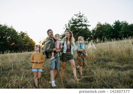 Family hiking together through countryside during summer camping trip. Family hiking together through countryside during summer camping trip. 142807377