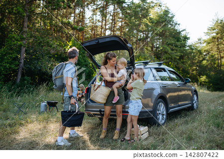 Family preparing for outdoor camping trip after traveling by car. Family preparing for outdoor camping trip after traveling by car. 142807422