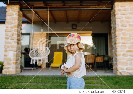 Toddler girl playing outside while family relaxes near their new home. Toddler girl playing outside while family relaxes near their new home. 142807463