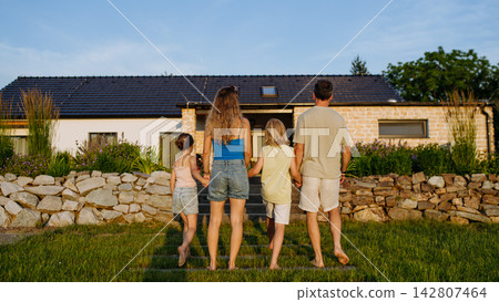 Happy young family spending summer evening together outside their new home. Happy young family spending summer evening together outside their new home. 142807464