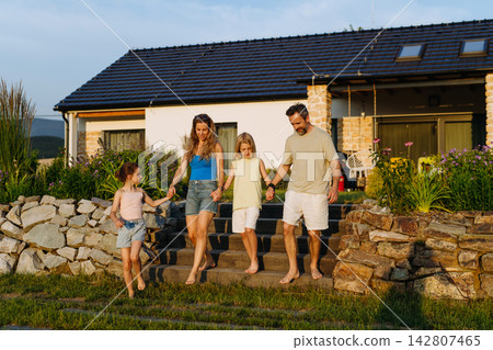 Happy young family spending summer evening together outside their new home. 142807465