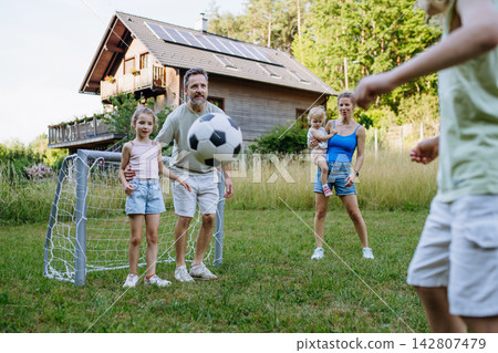 Family playing soccer together in backyard during summer. Family playing soccer together in backyard during summer. 142807479