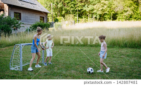 Mom and kids playing football in backyard during summer afternoon. Mom and kids playing football in backyard during summer afternoon. 142807481