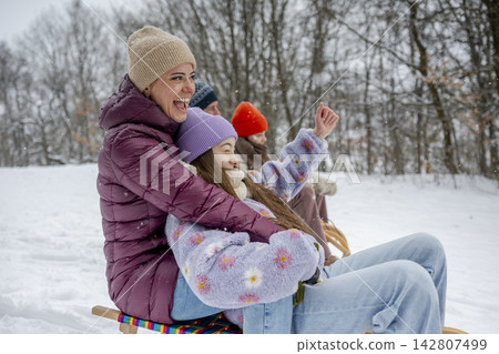Family enjoying winter sledding together on snowy hill. Family enjoying winter sledding together on snowy hill. 142807499