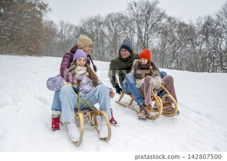 Family enjoying winter sledding together on snowy hill. Family enjoying winter sledding together on snowy hill. 142807500