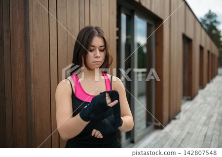 Woman preparing for fitness training with boxing wraps. Woman preparing for fitness training with boxing wraps. 142807548