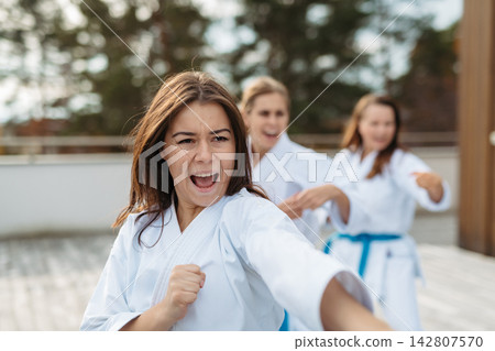 Confident women training karate together. Confident women training karate together. 142807570