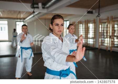 Focused female karate fighters practicing punch technique. Focused female karate fighters practicing punch technique. 142807578