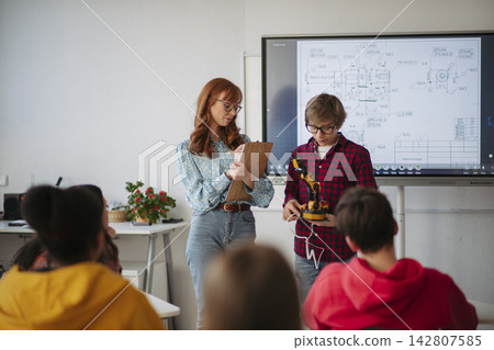 Teen boy explaining robotics project during science and technology class. 142807585