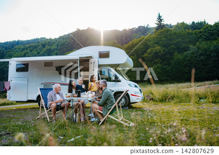 Multigenerational family having picnic dinner during summer caravan vacation. Multigenerational family having picnic dinner during summer caravan vacation. 142807629