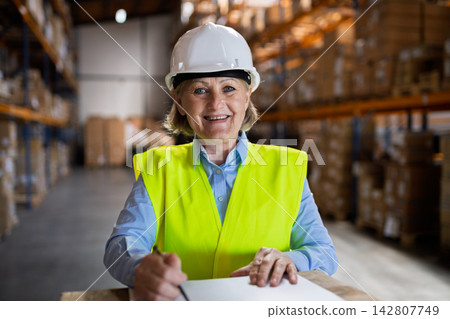 Senior woman manager or supervisor standing in a warehouse, arms crossed. Senior woman manager or supervisor standing in a warehouse, arms crossed. 142807749
