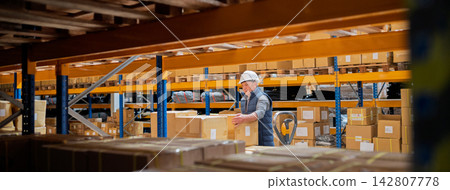 Older male warehouse worker working in big warehouse. Older male warehouse worker working in big warehouse. 142807778