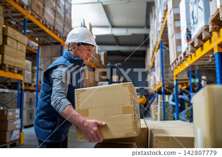 Older male warehouse worker working in big warehouse. Older male warehouse worker working in big warehouse. 142807779