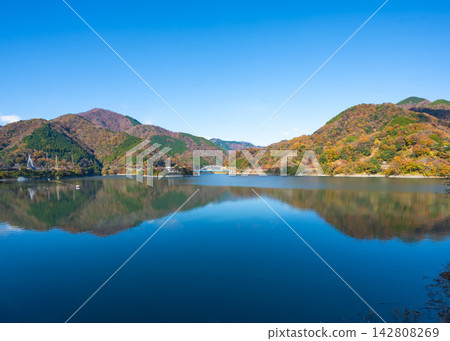 從湖岸邊望去,可以看到遠處山脈的秋葉倒映在丹澤湖的湖上。 從湖岸邊望去,可以看到遠處山脈的秋葉倒映在丹澤湖的湖上。 142808269