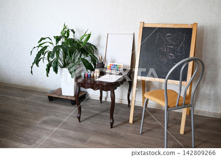 Creative workspace features painting supplies, brushes, and colorful materials ready for an art project at a desk Creative workspace features painting supplies, brushes, and colorful materials ready for an art project at a desk 142809266