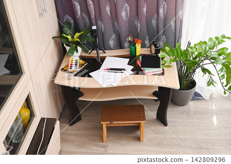 Creative workspace features painting supplies, brushes, and colorful materials ready for an art project at a desk Creative workspace features painting supplies, brushes, and colorful materials ready for an art project at a desk 142809296