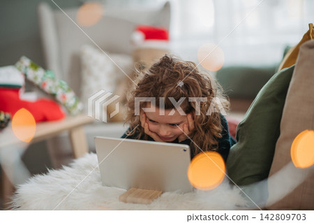 Little girl enjoying new tablet received as Christmas present at home. Little girl enjoying new tablet received as Christmas present at home. 142809703