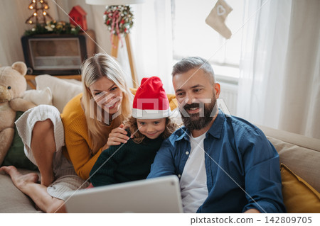 Family watching Christmas movie together on tablet during cozy holiday at home. Family watching Christmas movie together on tablet during cozy holiday at home. 142809705