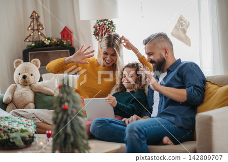Family making Christmas video call with relatives during holiday celebration at home. Family making Christmas video call with relatives during holiday celebration at home. 142809707