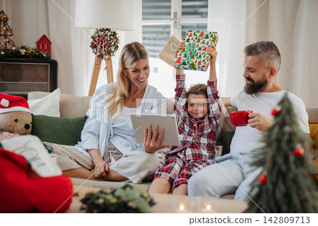 Family making Christmas video call with relatives during holiday celebration at home. Family making Christmas video call with relatives during holiday celebration at home. 142809713